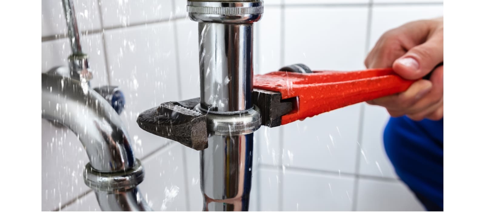 A wrench over-tightened on a chrome waste pipe, water spraying from the joint it has cracked